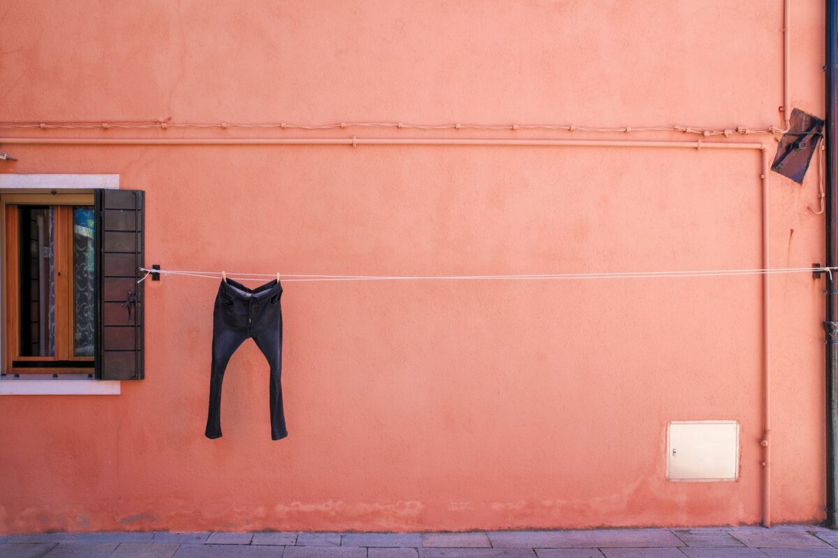 A pair of trousers drying on a line in front of an orange house