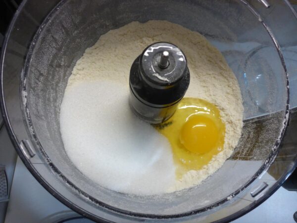 Photo of an egg and sugar added to the mixture in the food processor